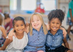 Image of three children sitting together smiling for the camera.